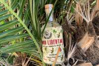 A bottle of "Ron Libertad" white rum surrounded by palm trees